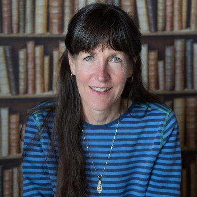 Picture of a woman with long dark rown hair, wearing a blue stripy top.